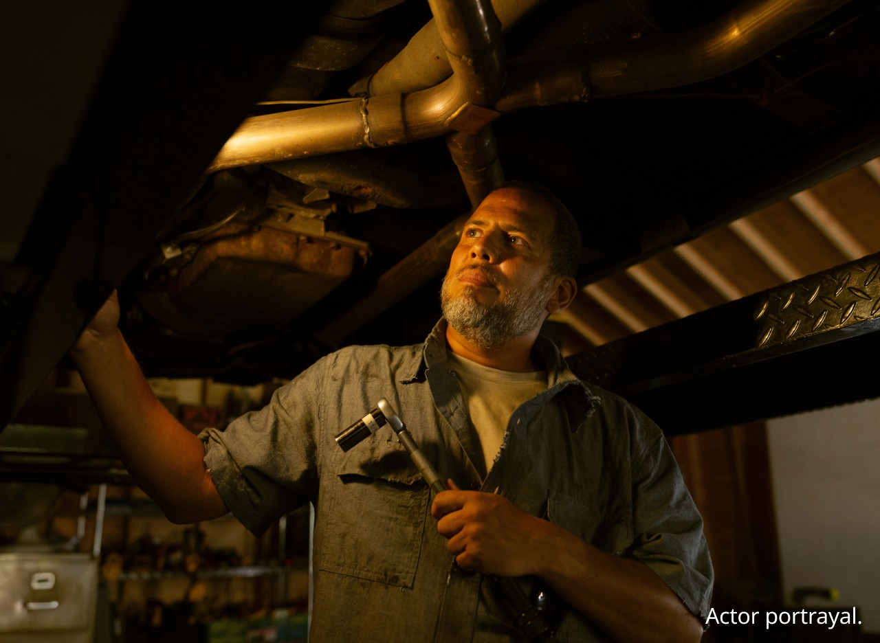 Man examining the undercarriage of a car